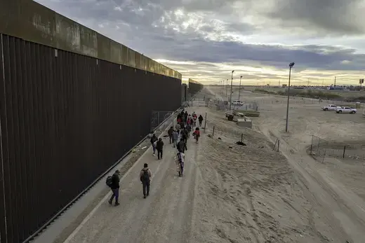 Migrants walk along the U.S.-Mexico border after crossing the Rio Grande into Texas.