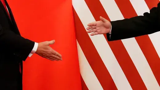 U.S. President Donald Trump and China's President Xi Jinping shake hands with their countries flags behind them.