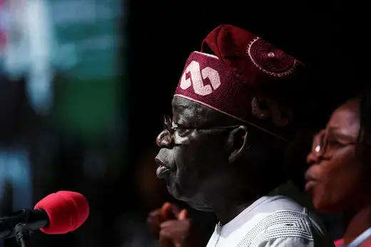 President Bola Tinubu is pictured by a microphone giving a speech. 