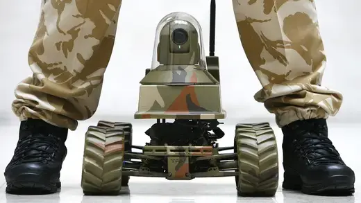 A marine stands above an Unmanned Vehicle Robot, Testudo, at the launch of the Defence Technology Plan in London.