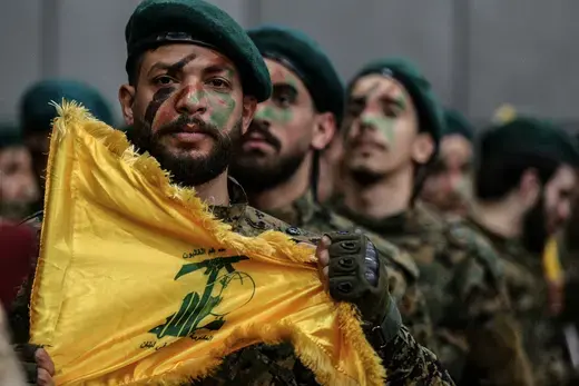  A man bearing a Hezbollah flag leads ranks of militants through Beirut’s southern suburb.