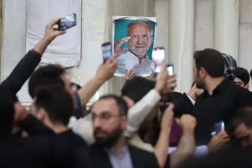 Someone holds a poster of President-Elect Masoud Pezeshkian above a crowd of his supporters