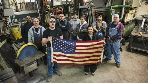 High angle view of workers holding American flag in factory.