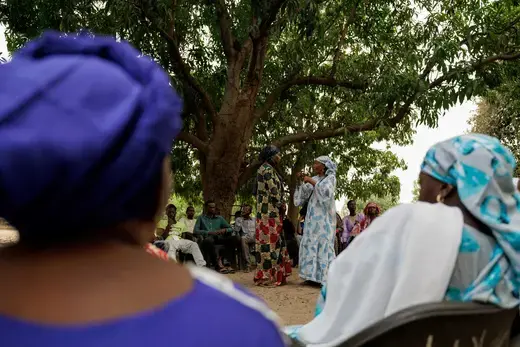 Gambian activist Fatou Baldeh listens to Fatou Ba, as she mediates a discussion about female genital mutilation (FGM) involving women and a handful of men sitting under a mango tree in Sintet, Gambia, June 8, 2024.