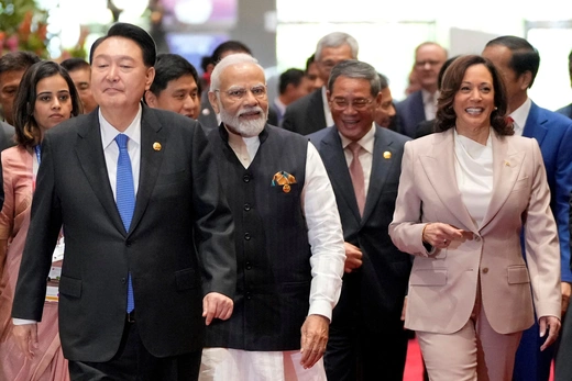 South Korean president wears a black suit while walking beside Indian Prime Minister Narendra Modi, who wears a black tunic, and Vice President Kamala Harris, who wears a light pink suit.