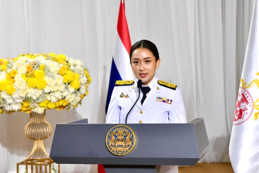 Woman wears white military uniform while standing at a podium addressing an audience.