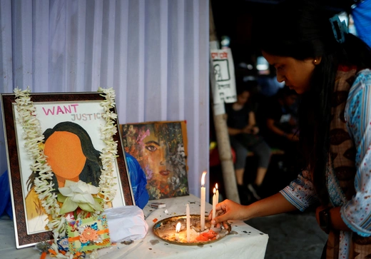 A woman lights a candle as she attends a protest condemning the rape and murder of a trainee medic, inside the premises of R G Kar Medical College and Hospital in Kolkata, India, August 20, 2024. 