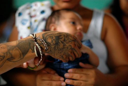 A gang member and inmate plays with his son, who is being carried by his partner, in a prison in Quetzaltepeque, on the outskirts of San Salvador June 16, 2012. 