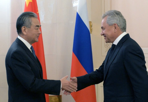 Russian Security Council Secretary Sergei Shoigu shakes hands with Chinese Foreign Minister Wang Yi.