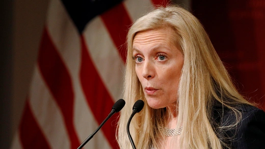 Federal Reserve Board Governor Lael Brainard speaks on stage foregrounding the U.S. flag.