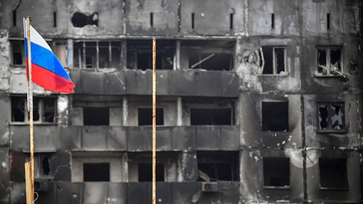 A Russian national flag flies by destroyed buildings in Eastern Ukraine.