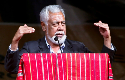 Timor's Prime Miinster stands at a podium with a red cloth over it while he gestures his hands.