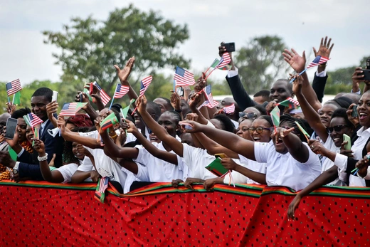 People cheer and wave American and Zambian flags during the visit of Vice President Kamala Harris in Lusaka, Zambia, on March 31, 2023. 