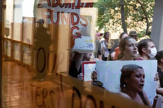 Abortion rights demonstrators hold up signs and drum against the the windows of Denton City Hall while police watch from the inside as Denton’s city council meets to vote on a resolution seeking to make enforcing Texas’ trigger law on abortion a low priority for its police force, in Denton, Texas, U.S. June 28, 2022. 