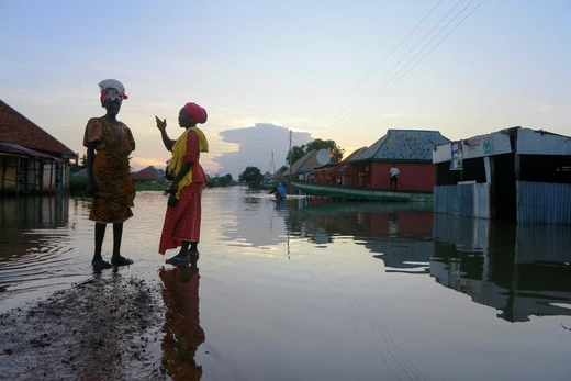 Two women wait for a canoe as flood overflows streets in Wadata in Makurdi, Nigeria, October 1, 2022. 