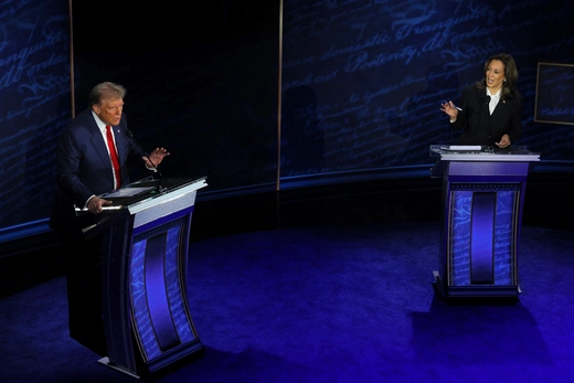 Both candidates stand at podiums with blue carpet and background.