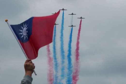 A spectator waves a Taiwanese flag as Taiwan's Air Force Thunder Tiger Aerobatics Team flies by during Taiwan's 113th National Day celebrations on October 10, 2024. Yan Zhao/AFP/Getty Images