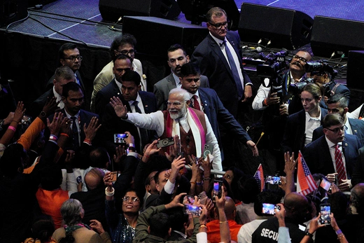 Prime Minister Modi, surrounded by a security detail, waves to the crowd.