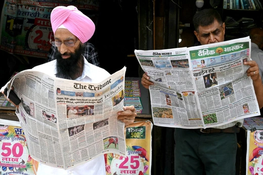 Men read local newspapers with front-pages news on US President Joe Biden's announcement of dropping out of the U.S. presidential race besides a stall in Amritsar, India, on July 22, 2024. Narinder Nanu/AFP/Getty Images