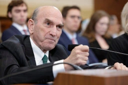 Man in green suit speaks into microphone