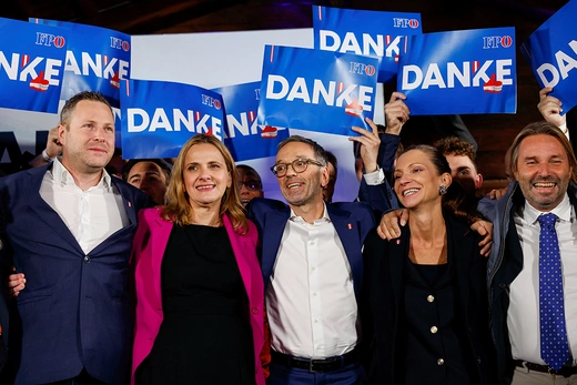 A group of members of Austria’s Freedom Party (FPÖ) celebrate their electoral win together on a brightly-lit stage. 