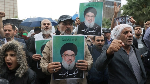 A crowd of mourners in Iran hold images of Hezbollah leader Sayed Hassan Nasrallah during a protest.