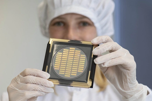 An engineer shows a wafer with photonic chips for quantum computing at the company Q.ANT.