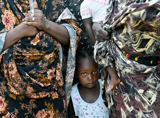 A child stands between two women at a school turned into a shelter, in Port Sudan, Sudan, August 29, 2024.