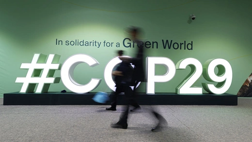 People walk past a COP29 logo during the United Nations Climate Change Conference (COP29), in Baku, Azerbaijan.