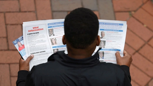 A man reads information pamphlets while waiting in line to vote outside a polling site in Charlotte, North Carolina.