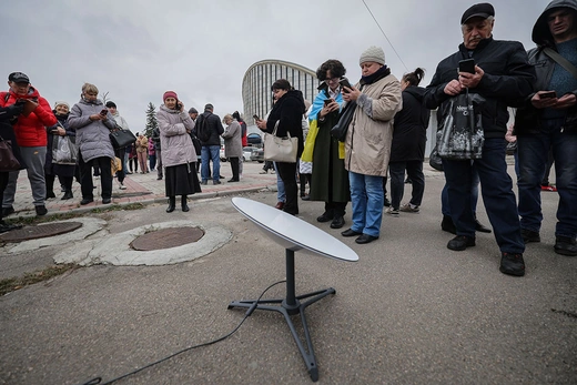 Local residents in Ukraine stand around a satellite using the internet from the Starlink network.