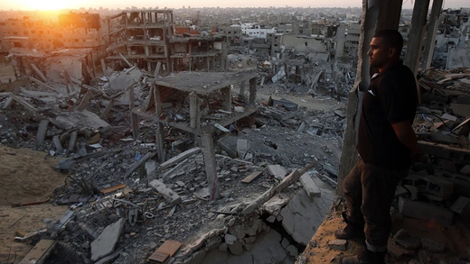 A Palestinian man looks out of his heavily damaged house at neighbouring houses which witnesses said were destroyed during the Israeli offensive, in the east of the Gaza strip.