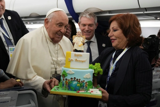 Pope Francis is presented with a colorful cake to celebrate his 88th birthday on a plane.