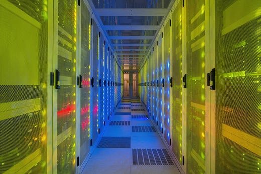 Multi colored server room of data center with multiple racks of computing equipment.