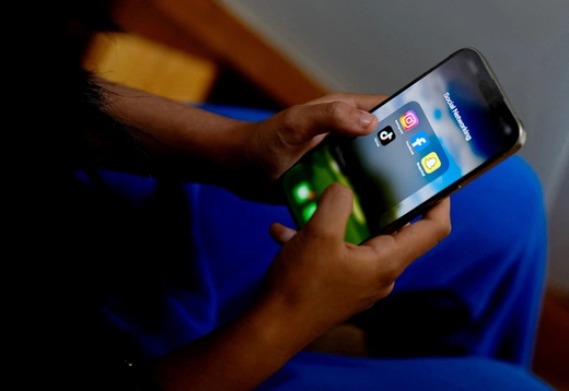 A high school student poses with her mobile showing her social media applications in Melbourne, Australia, November 28, 2024.