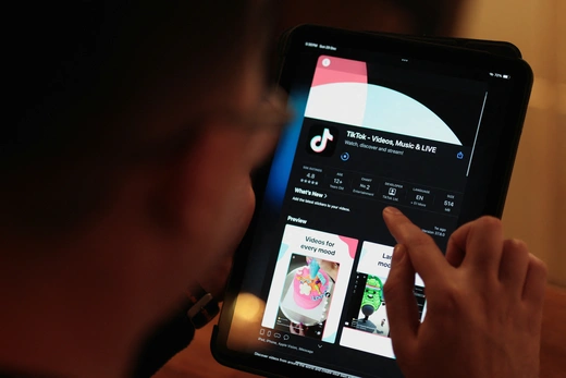 A man looks down at his tablet while downloading TikTok onto his device.