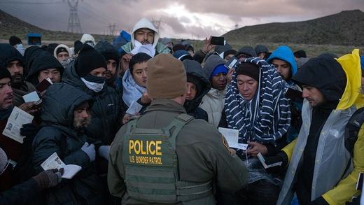 A Border Patrol agent processes asylum seekers at an improvised camp in near the U.S.-Mexico border.