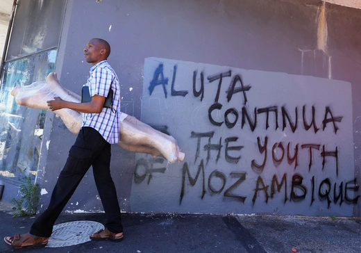 A man walks past graffiti reading Aluta Continua, which means "The struggle continues" for the youth in Mozambique, in Cape Town, South Africa, on November 18, 2024.