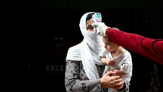 A health worker scans a resident with an infrared thermometer to check her temperature as a precautionary measure against the spread of Covid-19 in New Delhi, India.