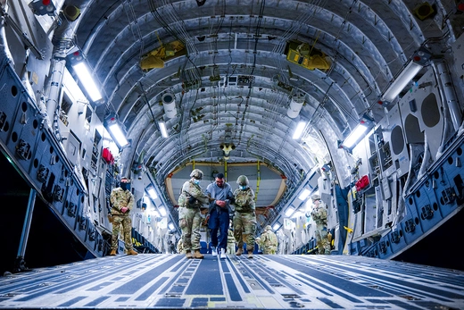 U.S. military personnel escort alleged members of Venezuela’s Tren de Aragua gang and the MS-13 gang off a plane in San Luis Talpa, El Salvador.