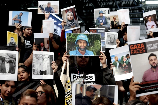Mexican journalists and students hold up signs of journalists in protest. 