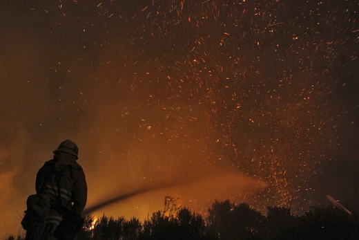 A firefighter douses embers from the Springs Fire at Point Mugu State Park, May 3, 2013.