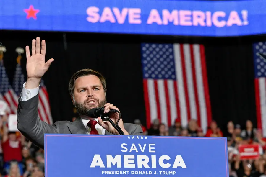 Republican VP Nominee J.D. Vance waves in front of a podium.
