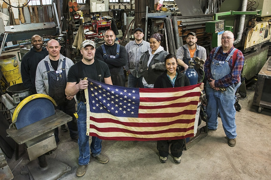 High angle view of workers holding American flag in factory.