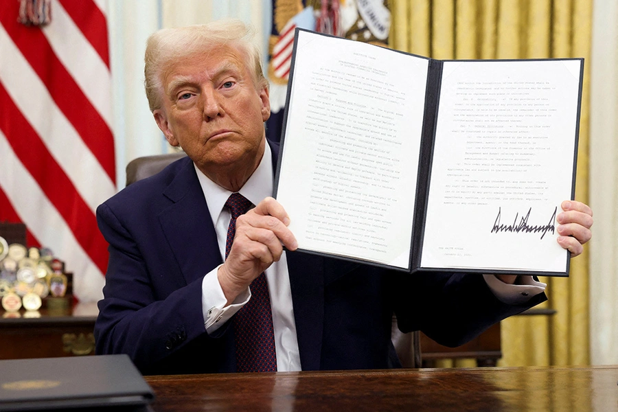 Donald Trump holds a signed executive order on cryptocurrencies in the Oval Office.