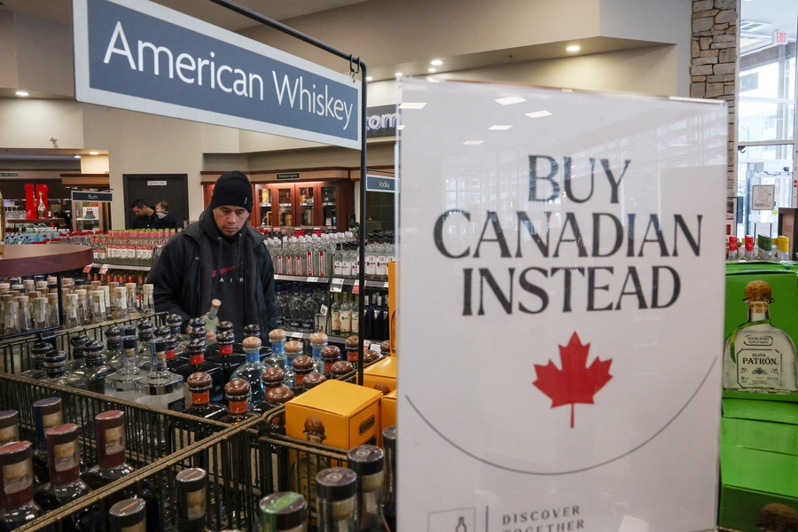 A customer holds a bottle as a sign that reads “Buy Canadian Instead” is displayed after the top five U.S. liquor brands were removed from sale at B.C. Liquor Stores, in Vancouver, British Columbia, Canada.