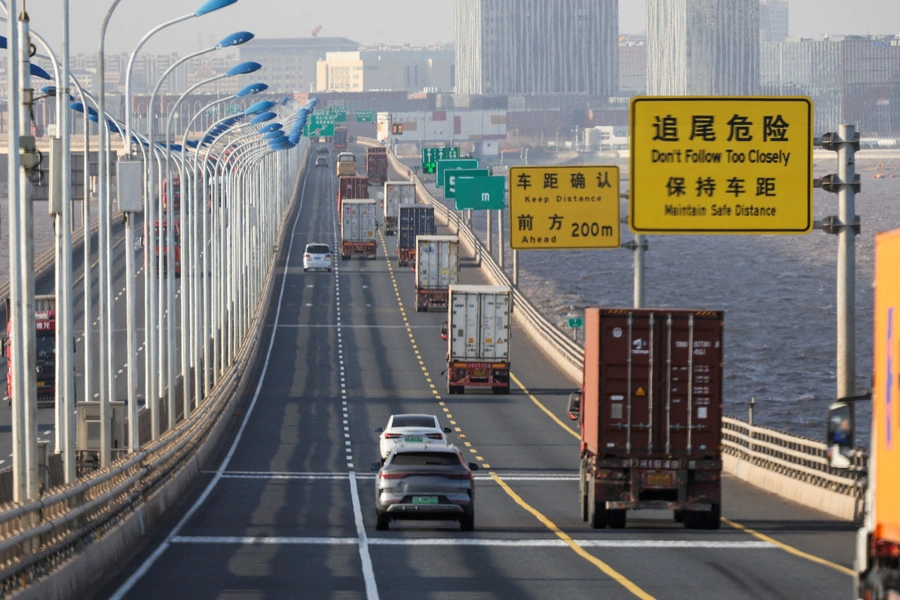 FILE PHOTO: Trucks loaded with shipping containers pass over Donghai Bridge to exit Yangshan Port outside of Shanghai, China, February 7, 2025. REUTERS/Go Nakamura