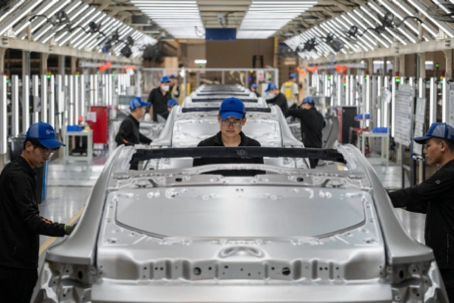 Workers check vehicle frames on the production line for electric vehicle maker Zeekr at its factory in Ningbo, China