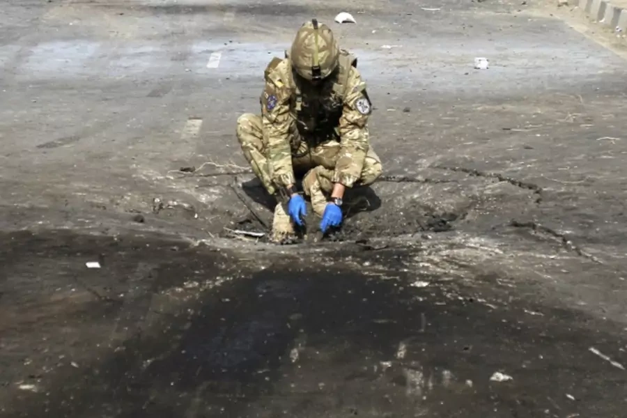 A soldier investigates the crater caused by an explosion at the site of a suicide attack in Kabul, Afghanistan, in November 2011 (Courtesy Reuters/Mohammad Ismail).