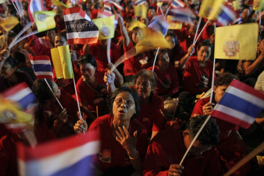 Red shirt supporters wave flags as thousands of people gather outside the Grand Palace to celebrate the birthday of Thailand's King Bhumibol Adulyadej in Bangkok.